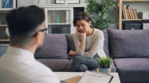 A person seated across from a counselor in a quiet, comfortable office setting, both engaged in relaxed conversation.
